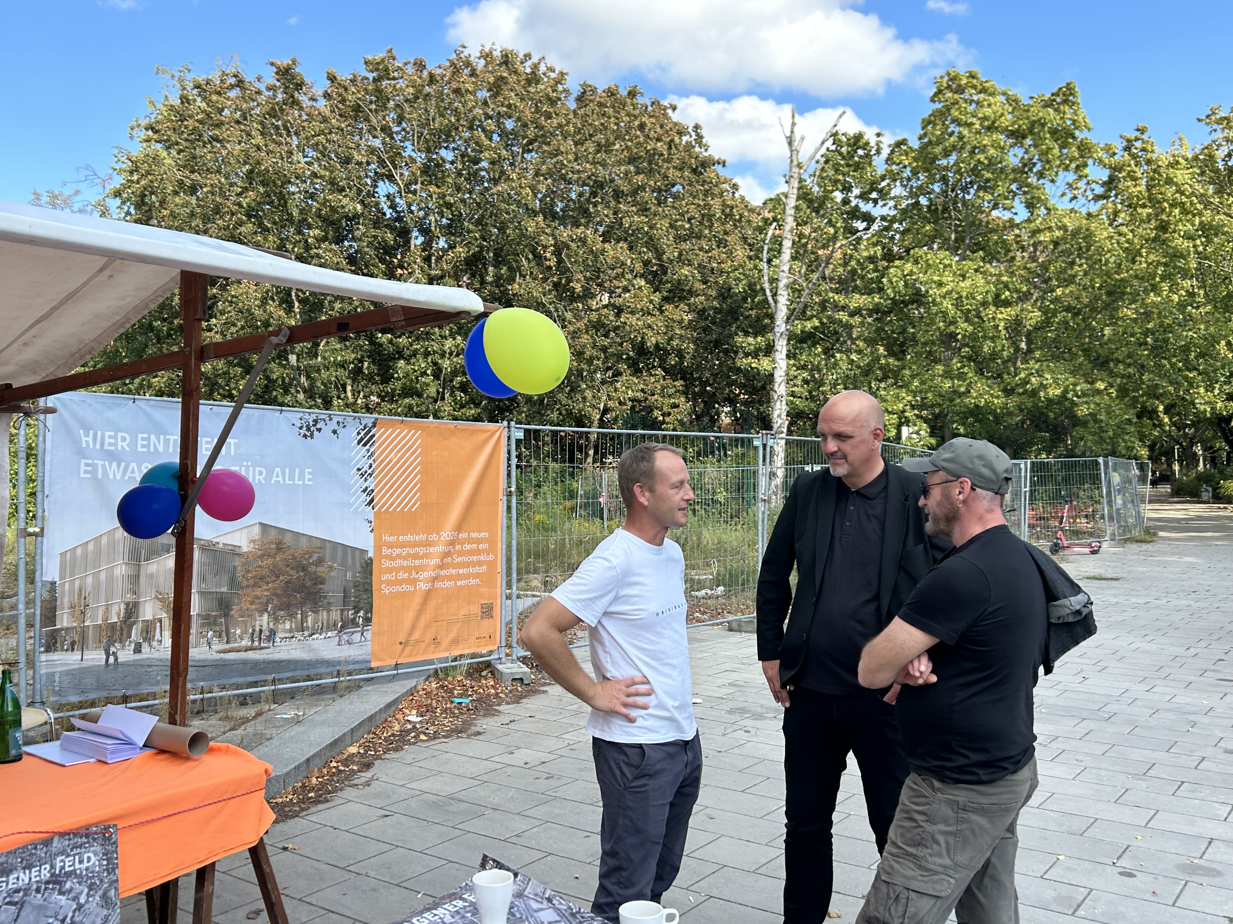 Personen im Gespräch für einem Marktstand