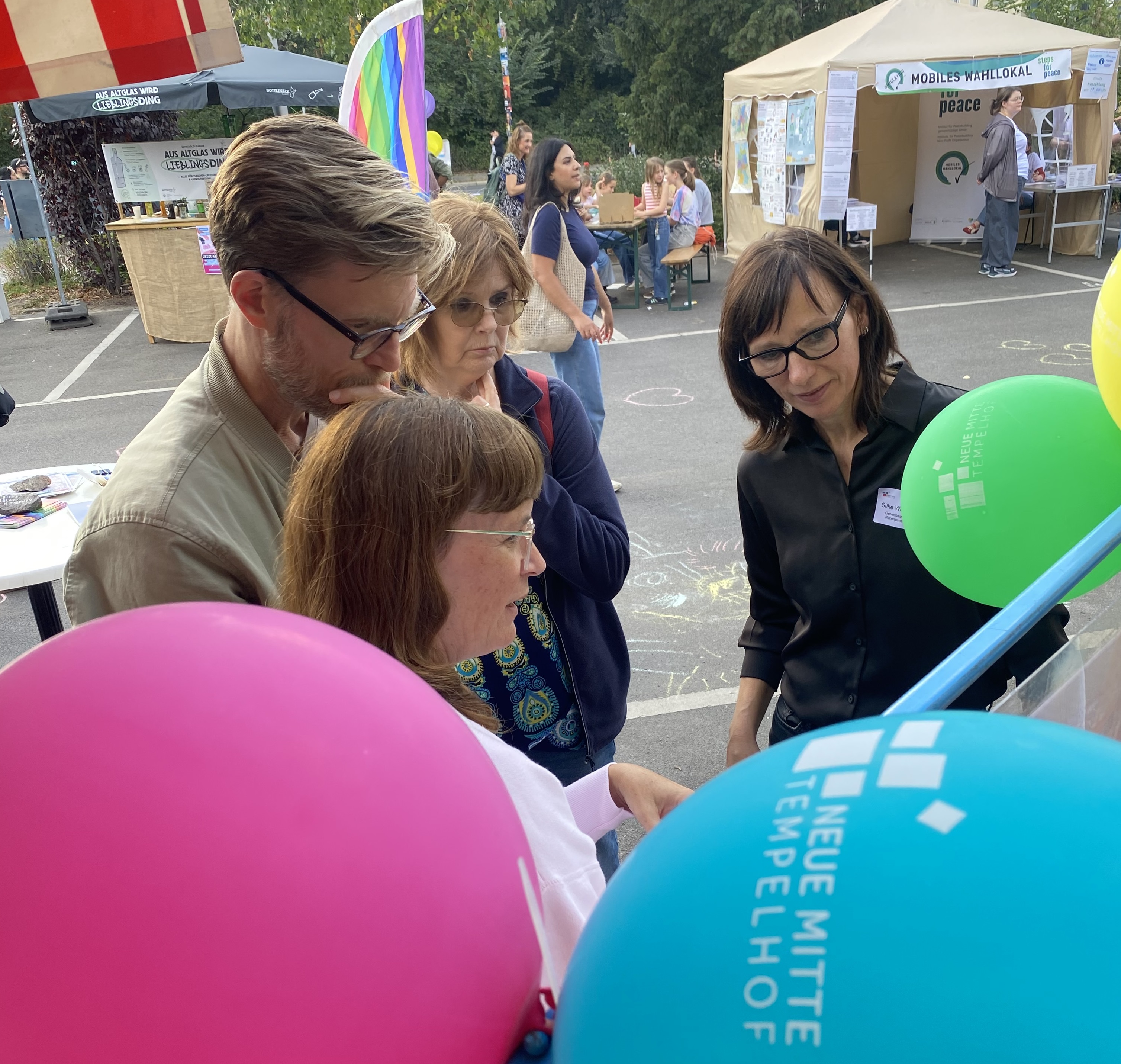 Menschen im Gespräch, im Vordergrund Luftballons